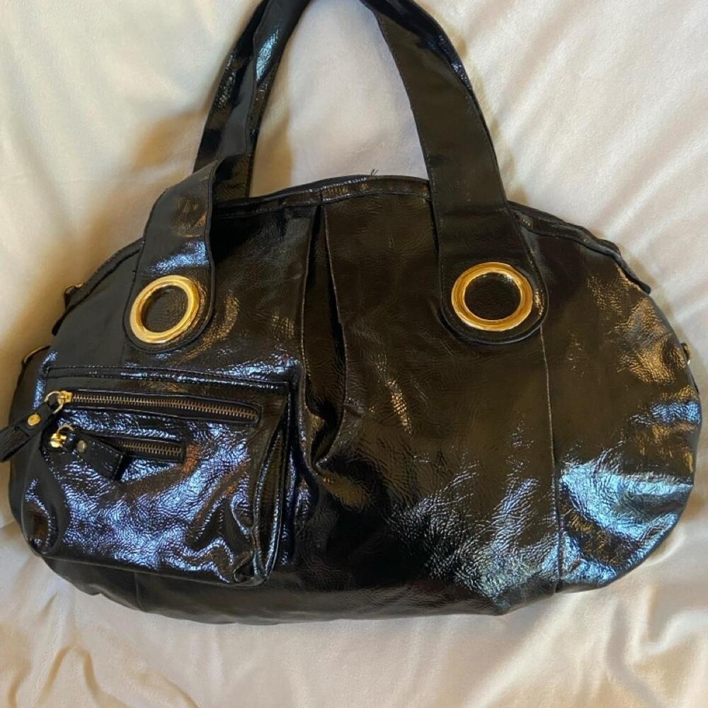 Black patent handbag with large gold accents . It’s large enough to double as a